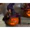 This image shows a Halloween witch decoration. It is made from a real dried gourd. Her carved face is lit up with a batter-operated candle.